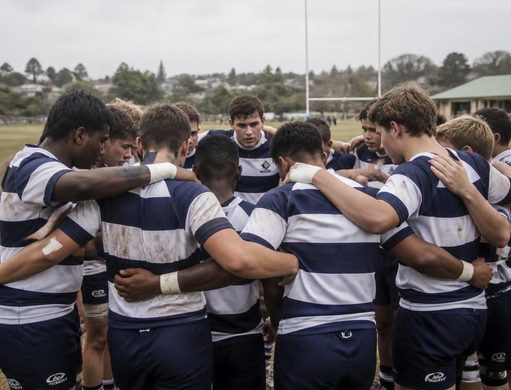 School rugby team in blue and white kit huddled on a training field